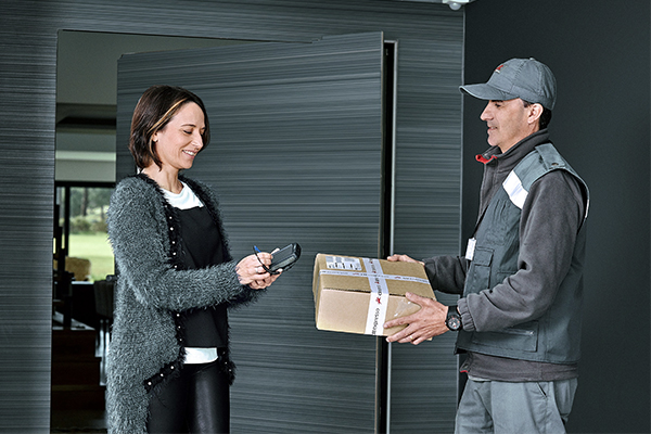 Carteiro a recolher encomenda na casa de uma senhora.